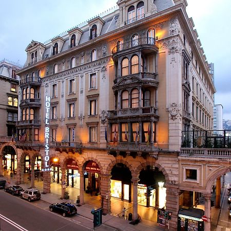 Hotel Bristol Palace Génova Exterior foto The photo shows a grand hotel building, likely the Hotel Bristol. It features an elegant architectural design with ornate details, including balconies and decorative moldings. The façade is illuminated, giving it a warm glow in the evening light. The