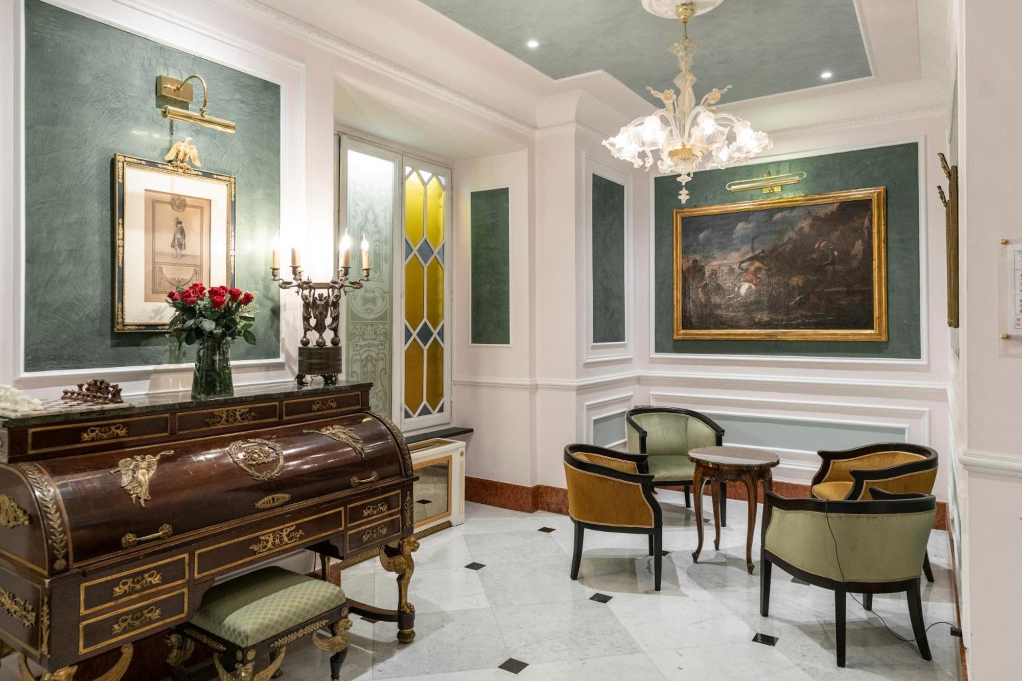 Hotel Bristol Palace Génova Exterior foto The photo shows a beautifully decorated interior space that appears to be a small living or reception area. It features elegant furniture, including a wooden writing desk or chest with intricate designs and several chairs with a mix of colors. 

The 