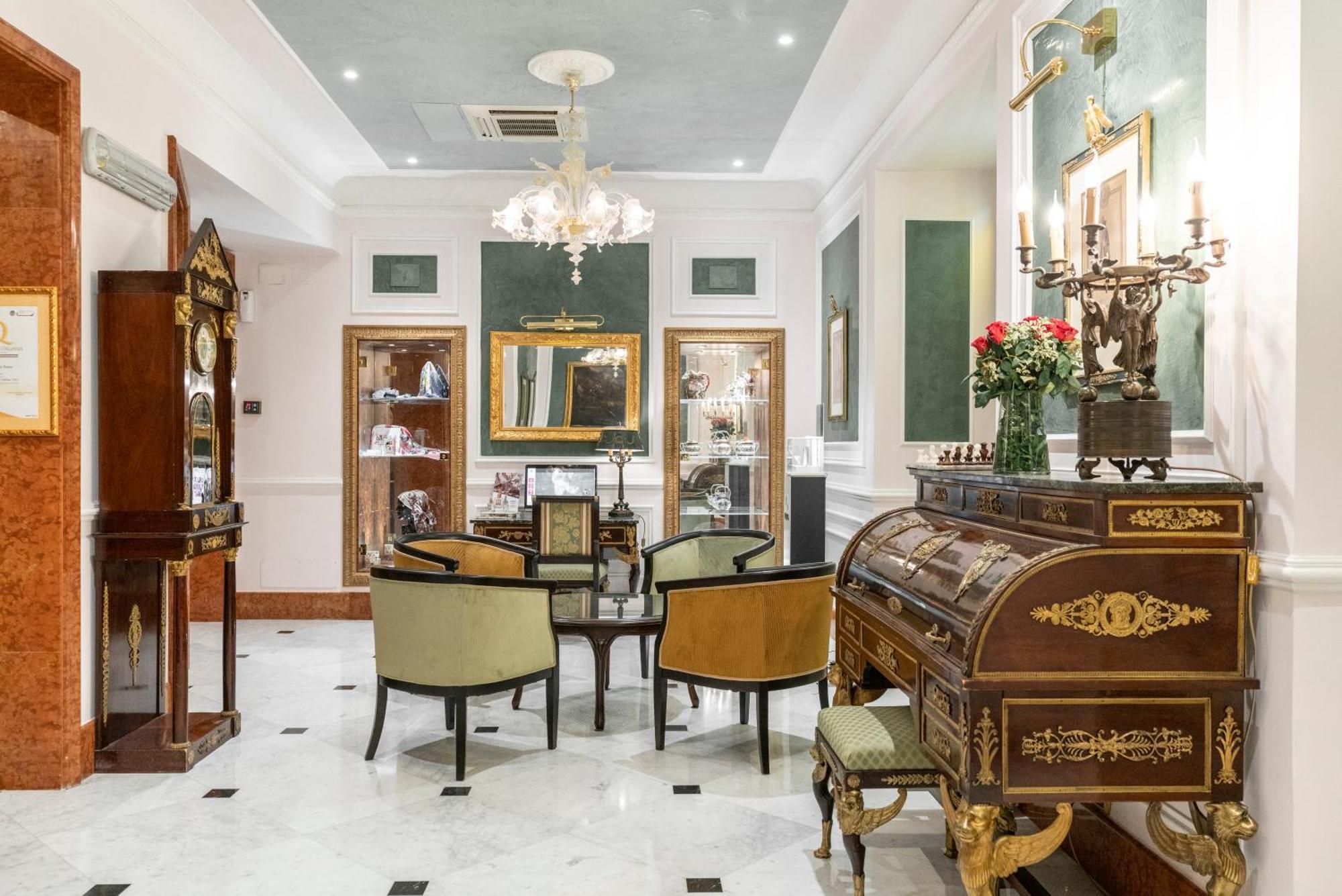Hotel Bristol Palace Génova Exterior foto The photo shows an elegantly furnished room that appears to function as a sitting area or parlor. The space features a chandelier hanging from the ceiling, providing soft lighting. In the center, there is a round table surrounded by upholstered chair
