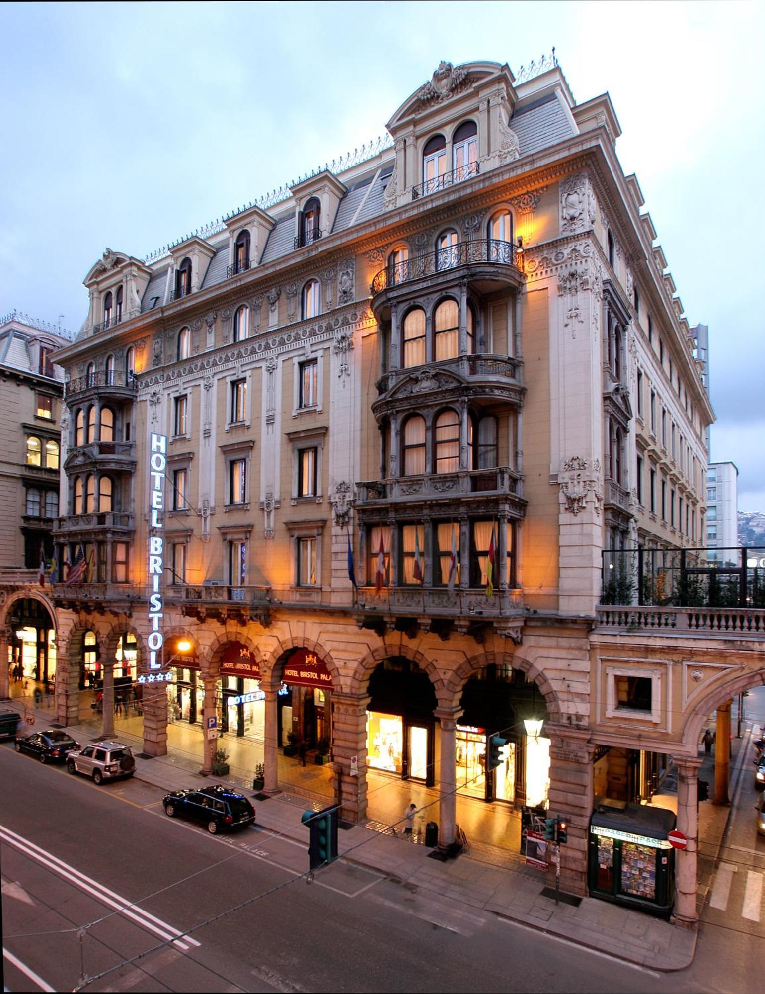Hotel Bristol Palace Génova Exterior foto The photo shows a grand hotel building, likely the Hotel Bristol. It features an elegant architectural design with ornate details, including balconies and decorative moldings. The façade is illuminated, giving it a warm glow in the evening light. The