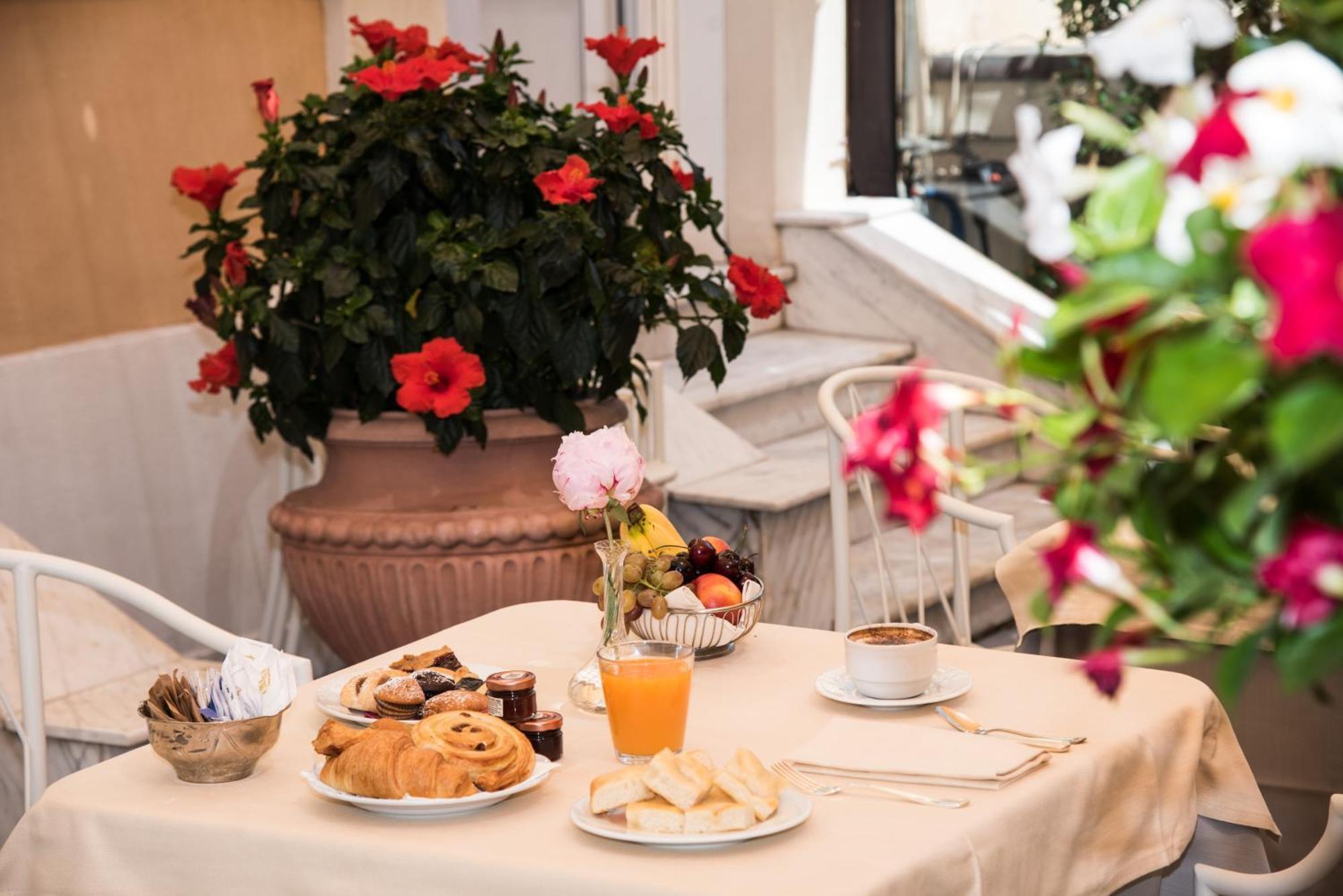 Hotel Bristol Palace Génova Exterior foto The photo shows a charming breakfast setup on a table covered with a light-colored tablecloth. There is a variety of food items, including pastry items like croissants and sweet rolls, alongside some fruit. Also visible is a small glass of orange jui